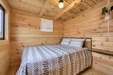Interior bedroom of a wooden cabin with knotty pine walls — useful to illustrate cabin accommodation options (gallery page).