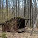 Side view of 3-sided wooden Adirondack shelter surrounded by trees in early spring.