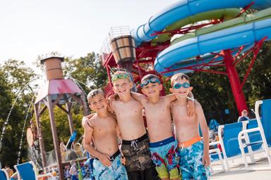 Pool area with large water slides in background and children in front — demonstrates the waterpark/waterslide attraction available on property.