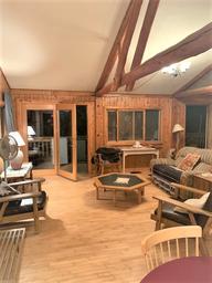 Interior living-room of a cabin/lodge (wood paneling, beams, seating) — lodging page image showing on-site accommodation common area useful for property gallery.