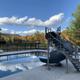 Clear photo of the campground swimming pool with slide, fenced pool deck and campground landscape/trees in the background — shown on the main site and gallery as the property’s pool.