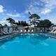 Heated outdoor pool lined with lounge chairs and flag pole at Palm View Gardens RV Resort site.