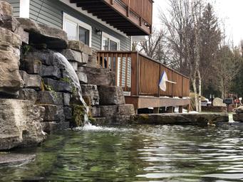 Small artificial waterfall and pond at the edge of a building deck — shows on-site water feature/landscaping and adjacent accommodations (source: homepage gallery).