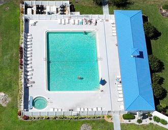 Aerial shot of the pool and adjacent building showing pool layout, surrounding deck chairs and spa — useful facility image (source: ‘Pool-aerial-Oct 2023’).