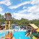 Ground-level photo of the pool/waterpark area with slides, play structures and lounge seating — clear view of on-site aquatic amenities.