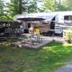 RV site with full hookup fifth‑wheel, patio area, picnic table and fire pit — depicts the campsite setup and guest accommodations (used on the campground’s main page content).