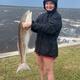 Shoreline/bay view showing a guest with a large fish and the water in the background; supports activity (fishing) and proximity to Ochlockonee Bay. 