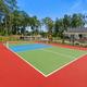 Recreation court (pickleball/tennis) with clubhouse and playground visible beyond — useful to show on-site activities and open recreation space.