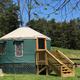 Close view of a raised yurt with entrance steps and surrounding lawn — good detail of the on-site lodging unit and grounds.