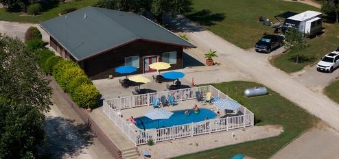 Close aerial of the pool area and adjacent building with surrounding parking/RV spaces — useful facility photo (homepage slide).