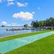 Lakeside view showing shuffleboard court, docks and shoreline — highlights waterfront amenities and open lawn. Image is part of the property photo set on the resort page (page: Lake Gaston RV Camping | Thousand Trails RV Campground, URL provided).
