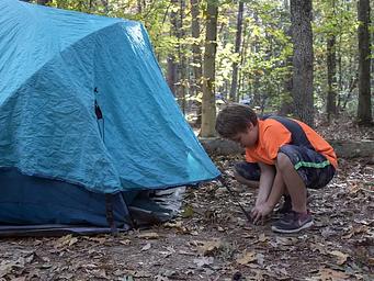 A young man sets up a blue tent