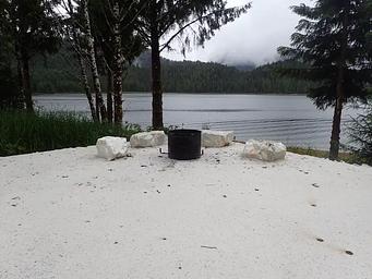 combination fire pit and fire grill at campsite with view of ocean