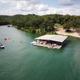 Aerial view of the resort’s covered dock/boat slip and adjacent shoreline with boats and people on the water — strong overview of the property’s lakeside layout. Sourced from the site’s hero/background images for the resort.