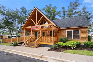 Exterior of the log-style clubhouse/office building on the campground grounds — clear view of the building style and entrance, helpful to show on-site facilities; matches homepage gallery context.