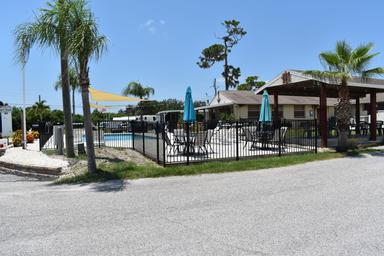Empty outdoor pool area with umbrellas and chairs on a sunny day.