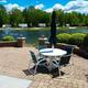 Patio with table and umbrella overlooking a pond with RV sites across the water — illustrates a premium lakeside site and patio area promoted on the rentals page.