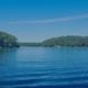 Wide, high-quality waterscape view of Peters Pond showing the pond and tree-lined shore — good overview shot from the property homepage (site main banner).