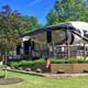 Close view of a full‑hookup RV on a prepared site with decking and landscaping — illustrates individual site quality (used as a campsite/hero image on the site).