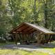 A brown picnic shelter with green trees in the background