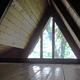 Triangular loft window of a wood cabin showing view of trees
