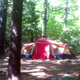 Large tent pitched among trees showing campsite layout and wooded surroundings — useful campsite view from the campground gallery.