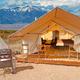 Clear exterior photo of a furnished glamping tent on a wooden platform with Great Sand Dunes / mountain backdrop — matches 'Glamping Tents' hero image on the property homepage and shows guest accommodation and site setting.