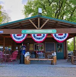 Photo of the campground office/pavilion storefront with visible Glacier Valley Campground sign and seating — useful for showing on-site facilities and check-in area.