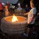 Nighttime scene of a stone fire pit with guests (children/adults) gathered — shows a communal amenity and guest experience on the property.