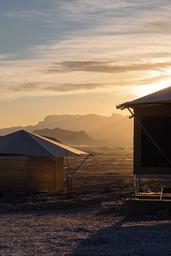 Exterior of luxury safari tents with sunrise views of the Chisos Mountains at Camp Elena in Terlingua, Texas, near Big Bend National Park.