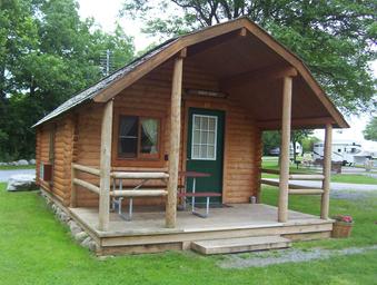 Front view of a rustic cabin on a grassy site with nearby RVs visible — useful to show cabin lodging option on the campground (file from the campground 'waystostay' photos).