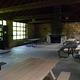 Inside view of the Black River Harbor Pavilion showing the set up of the room with 5 picnic tables, trash can, and fireplace.