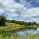 Scenic pond with surrounding meadow and trees — useful for showcasing on‑site natural features and grounds (appears on the property home page).