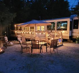Decorated campsite at Sleepy Hollow campground with RV, firepit, lights, and chairs.