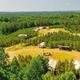 Clear aerial overview showing the campground layout: tents/cabins, central fire pit area, pavilion, surrounding forest — matches homepage hero-style images of Nine Pines Retreats and establishes property context and scale.