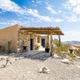 Exterior view of a stone/Adobe-style casita with pergola and surrounding landscape — useful for showcasing individual lodging and site character (from Casitas page).