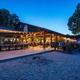 Evening shot of the outdoor dining area and restaurant veranda on the sand — shows dining facilities and beachfront atmosphere referenced on the site (used in page hero/background).