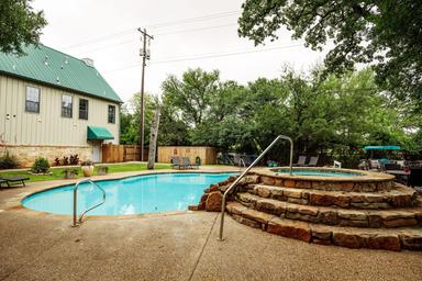 A large swimming pool with a hot tub in front of a building.