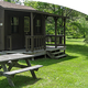 Photograph of a small rustic cabin with picnic table on grass — clearly shows on-site cabin accommodation offered by the property (appears on the campground’s cabin/cottage section).