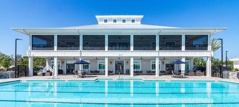 Wide frontal shot of the clubhouse building with the main resort pool in foreground — demonstrates main amenity and architecture (used on the home page).