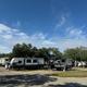 A row of rvs parked in a lot with trees in the background.