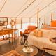 Interior glamping tent/living setup with bed and seating — good detailed photo of tent accommodation furnishings and guest space (safari/tent interior gallery).