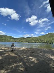 Sandy beach and lake view with lifeguard chair and mountains in background — shows the campground’s swimming/beach area (file named Beach-2025 on the site).