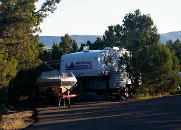 RV Trailer and boat parked in a camping site spur.