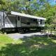 Clear photo of an RV on a gravel pad with picnic table and campsite furnishings — good example of the campground’s RV site offering. Matches homepage social image on property site.