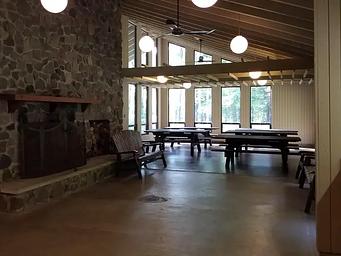 Inside of the Clark Lake pavilion showing picnic tables, benches, and fireplace.