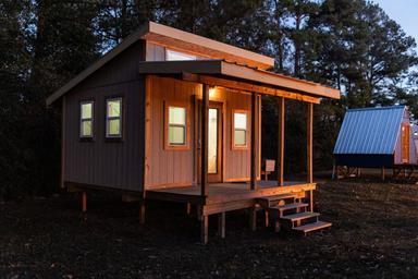 Twilight exterior of a tiny cabin with lit porch; good complementary view of lodging ambience and on‑site accommodations from the property gallery.