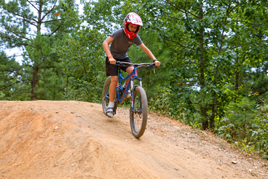 Young rider biking on a wooded trail at Asheboro Jellystone Park
