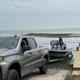 Clear on-property scene showing a pickup towing a boat at a shoreline/boat‑launch area — matches marina/boat launch facility referenced on the park website (Fishing & water activities).