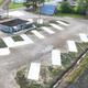 Aerial drone view of a new gravel RV park with empty concrete pads, hookup pedestals, a gray office building, and